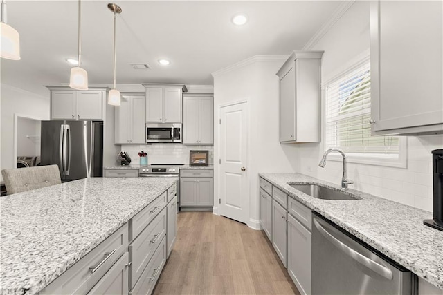 kitchen with appliances with stainless steel finishes, a sink, gray cabinets, decorative backsplash, and crown molding