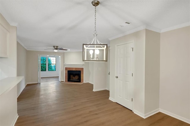 unfurnished living room with crown molding, hardwood / wood-style flooring, a tile fireplace, and ceiling fan