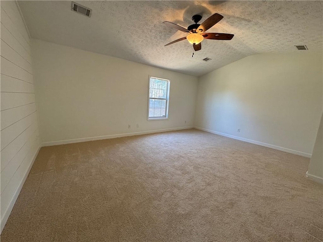 empty room featuring vaulted ceiling, a textured ceiling, visible vents, and a ceiling fan