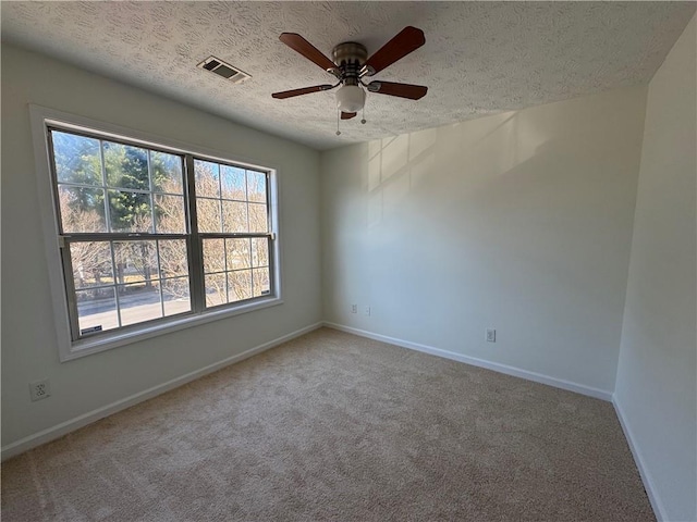 carpeted empty room featuring a ceiling fan, baseboards, visible vents, and a textured ceiling