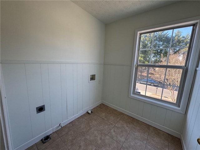 washroom featuring a wainscoted wall, hookup for a washing machine, hookup for an electric dryer, a textured ceiling, and laundry area