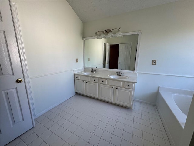 bathroom with a textured ceiling, double vanity, a sink, and a bath