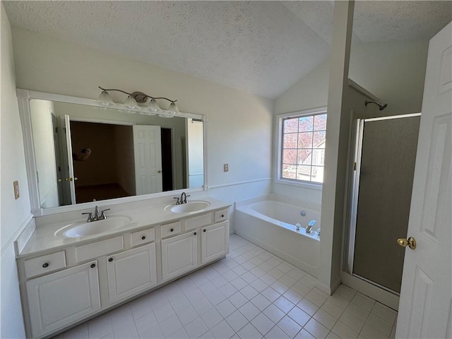 full bath with a textured ceiling, double vanity, a stall shower, and a sink