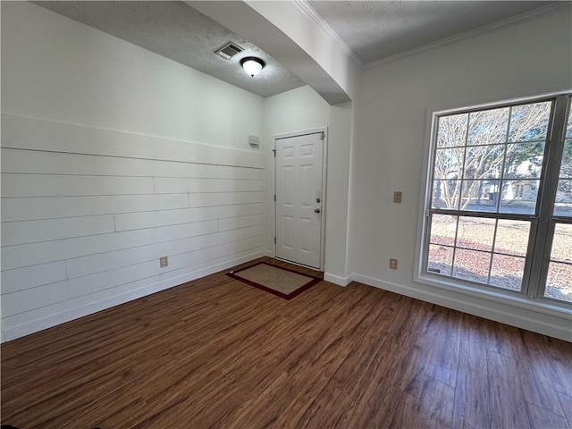 foyer entrance featuring a textured ceiling, dark wood-type flooring, visible vents, and crown molding