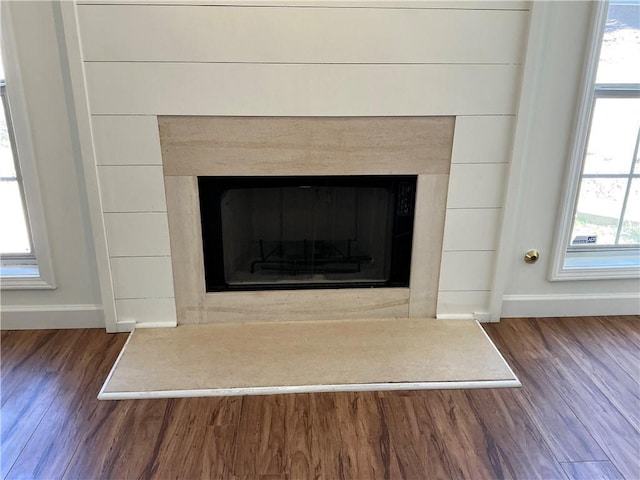 interior details featuring a fireplace with raised hearth, baseboards, and wood finished floors