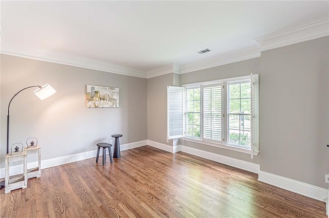 unfurnished room with baseboards, crown molding, visible vents, and wood finished floors