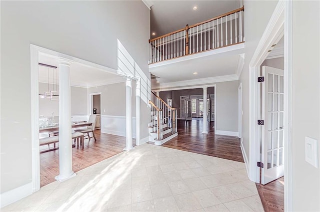 foyer with french doors, ornate columns, crown molding, stairway, and a high ceiling