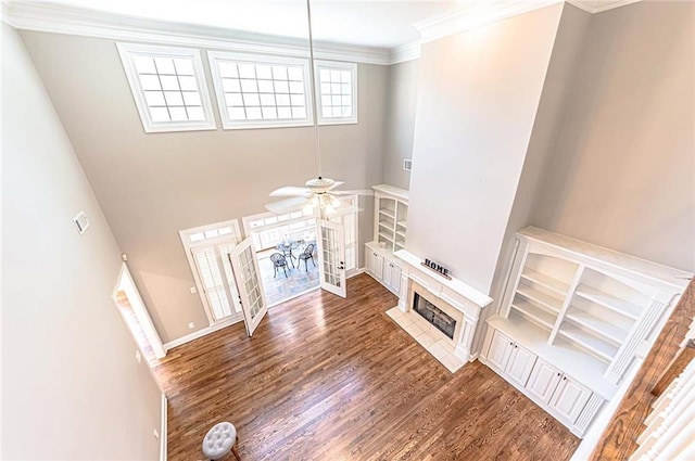 unfurnished living room with a ceiling fan, baseboards, ornamental molding, wood finished floors, and a fireplace