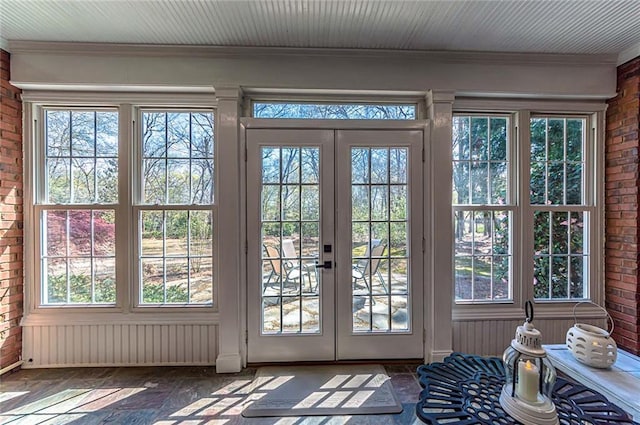 doorway to outside featuring a wealth of natural light and brick wall