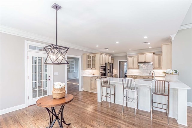 kitchen featuring a sink, a kitchen breakfast bar, crown molding, cream cabinetry, and appliances with stainless steel finishes