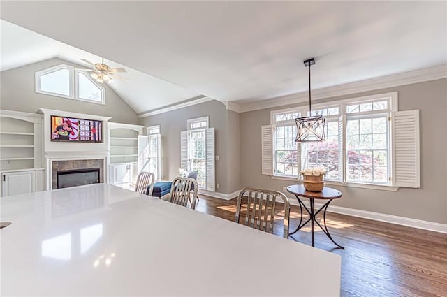 dining space with a premium fireplace, baseboards, ceiling fan with notable chandelier, and dark wood-type flooring
