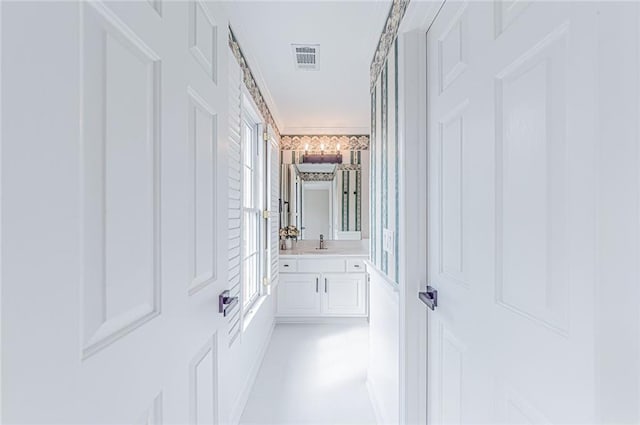hall featuring crown molding, visible vents, and a sink