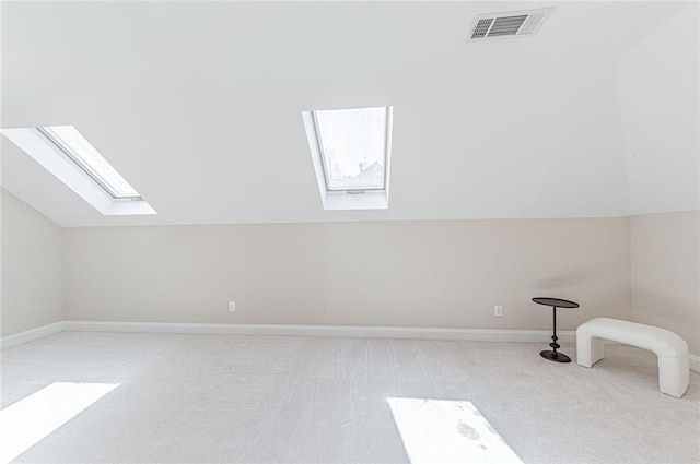 bonus room featuring vaulted ceiling with skylight, light carpet, baseboards, and visible vents