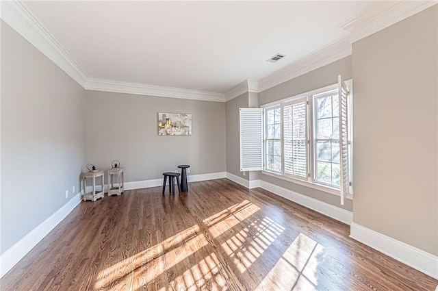 empty room with wood finished floors, baseboards, and ornamental molding