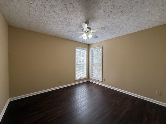 empty room featuring dark wood-style floors, ceiling fan, a textured ceiling, and baseboards