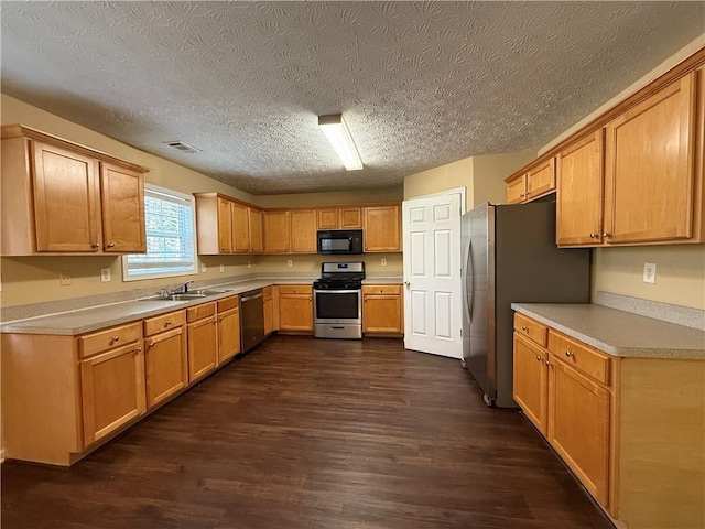 kitchen with dark wood finished floors, stainless steel appliances, light countertops, visible vents, and a sink