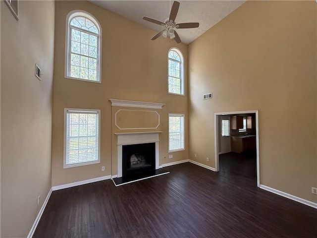 unfurnished living room with plenty of natural light, visible vents, and a fireplace with raised hearth