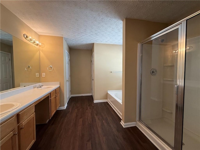 bathroom with a garden tub, a shower stall, a textured ceiling, and wood finished floors