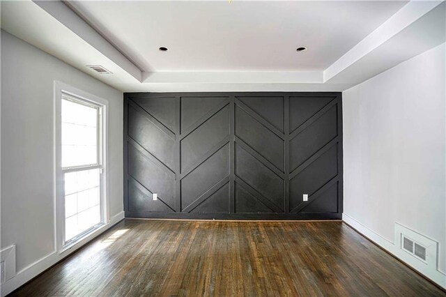 empty room featuring a tray ceiling and dark wood-type flooring