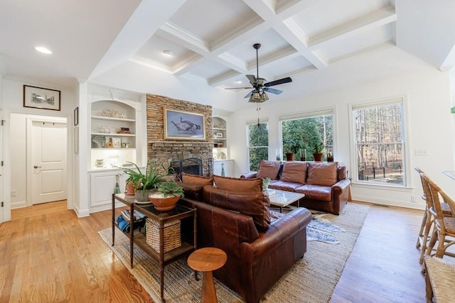 living room featuring beam ceiling, coffered ceiling, a fireplace, and light wood-style floors