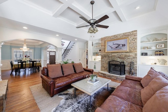 living area featuring built in features, wood finished floors, arched walkways, wainscoting, and a fireplace