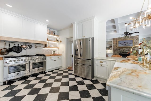 kitchen featuring a fireplace, a sink, light countertops, appliances with stainless steel finishes, and white cabinetry