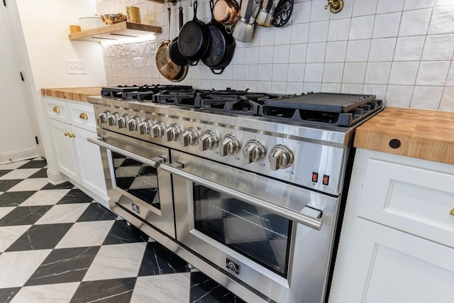 kitchen with open shelves, range with two ovens, butcher block countertops, white cabinetry, and backsplash