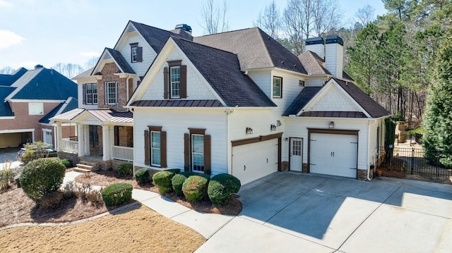 modern farmhouse featuring fence, a standing seam roof, an attached garage, a chimney, and concrete driveway