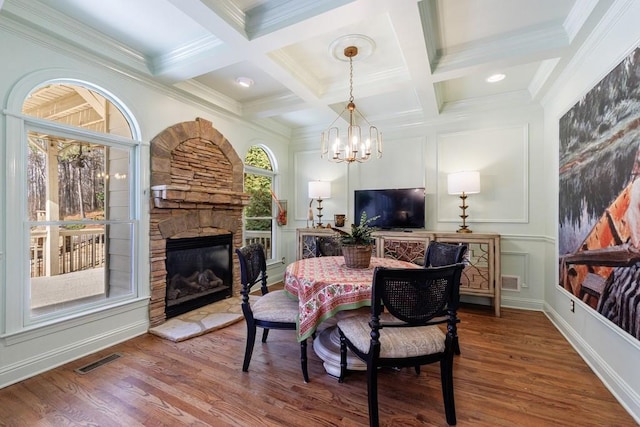 dining area with wood finished floors, a decorative wall, visible vents, and beamed ceiling