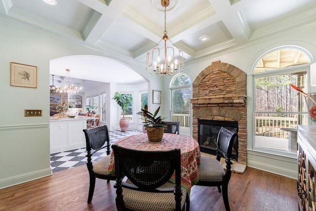 dining area featuring an inviting chandelier, a fireplace, dark wood-type flooring, and beam ceiling