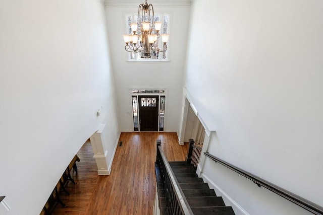 entryway with baseboards, stairway, a high ceiling, an inviting chandelier, and wood finished floors