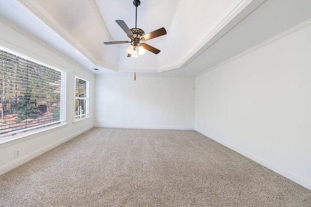 empty room featuring a tray ceiling, light colored carpet, baseboards, and ornamental molding