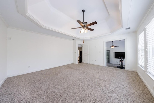 unfurnished room featuring a tray ceiling, plenty of natural light, light colored carpet, and visible vents