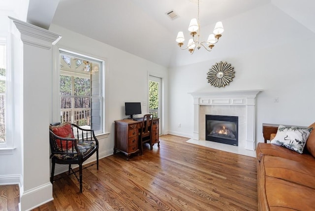 interior space with visible vents, wood finished floors, baseboards, vaulted ceiling, and a tile fireplace