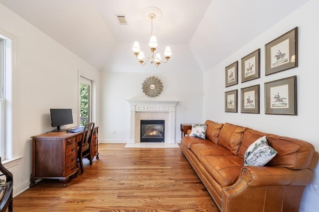 living room featuring visible vents, baseboards, a fireplace with flush hearth, light wood-type flooring, and lofted ceiling