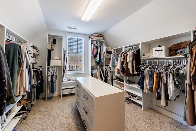 walk in closet with visible vents, lofted ceiling, and light carpet