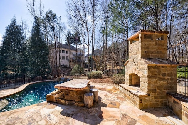 view of swimming pool with a fenced in pool, a patio, an outdoor stone fireplace, and fence