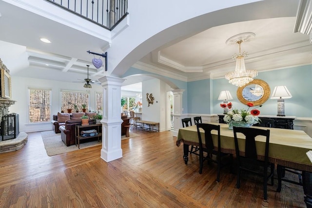 dining space with a wealth of natural light, decorative columns, arched walkways, and wood finished floors