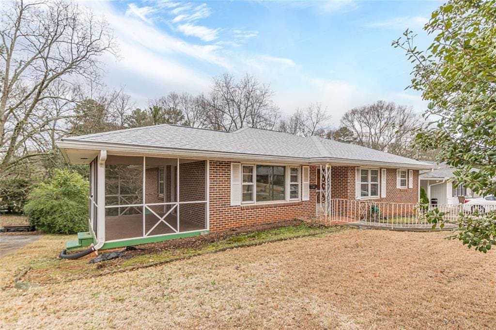 single story home with a front lawn and a sunroom