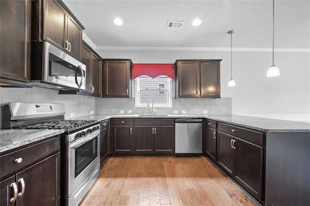 6535 Crosscreek Ln, Flowery Branch, GA 30542 - kitchen with appliances with stainless steel finishes, crown molding, a peninsula, light stone countertops, and dark brown cabinetry