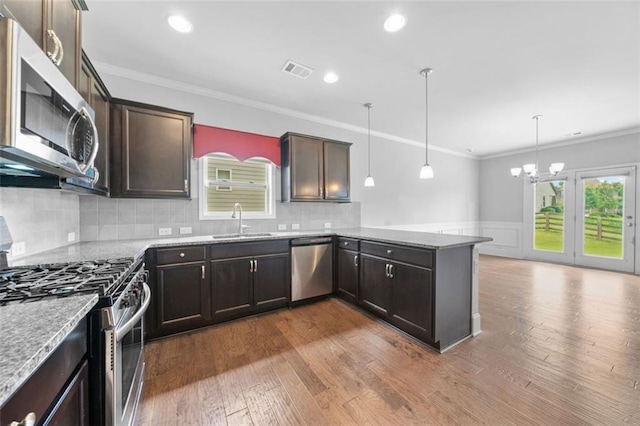 6535 Crosscreek Ln, Flowery Branch, GA 30542 - kitchen with appliances with stainless steel finishes, a peninsula, dark brown cabinets, a chandelier, and a wainscoted wall