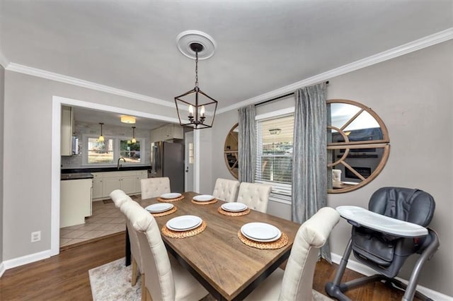 dining space featuring crown molding, sink, hardwood / wood-style floors, and an inviting chandelier