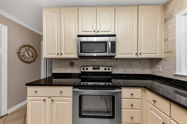 kitchen with light tile patterned floors, appliances with stainless steel finishes, cream cabinets, ornamental molding, and decorative backsplash