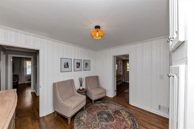 sitting room with dark wood-type flooring and ornamental molding