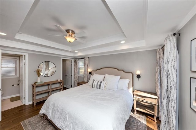 bedroom featuring dark hardwood / wood-style floors, ornamental molding, a raised ceiling, and ceiling fan