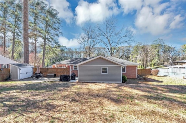 back of house with a lawn, a patio area, and a storage unit