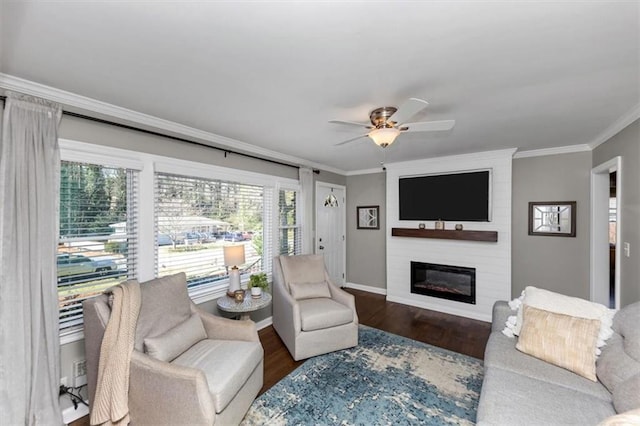 living room with ceiling fan, a large fireplace, ornamental molding, and dark hardwood / wood-style flooring