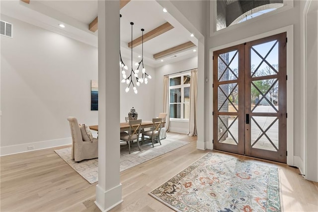 foyer entrance featuring light wood finished floors, baseboards, beam ceiling, french doors, and a notable chandelier