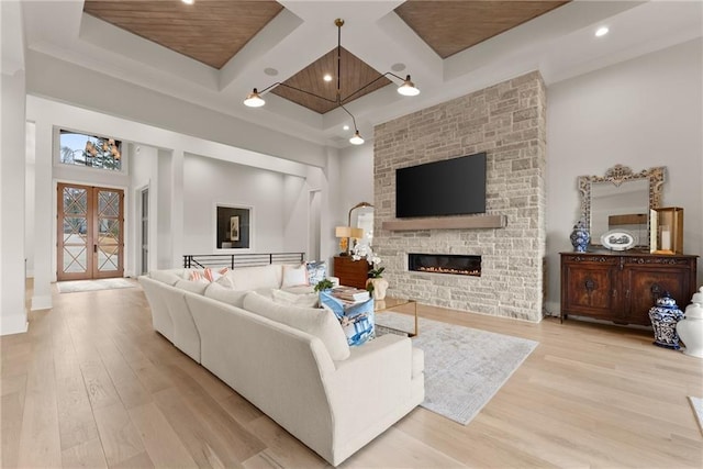 living area with beamed ceiling, coffered ceiling, a fireplace, and wood finished floors