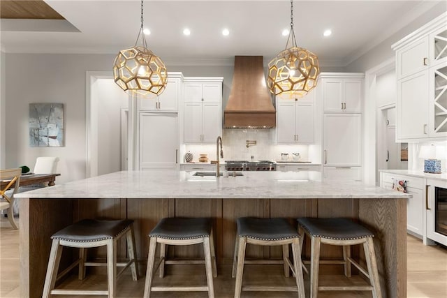 kitchen with a sink, tasteful backsplash, crown molding, and custom range hood